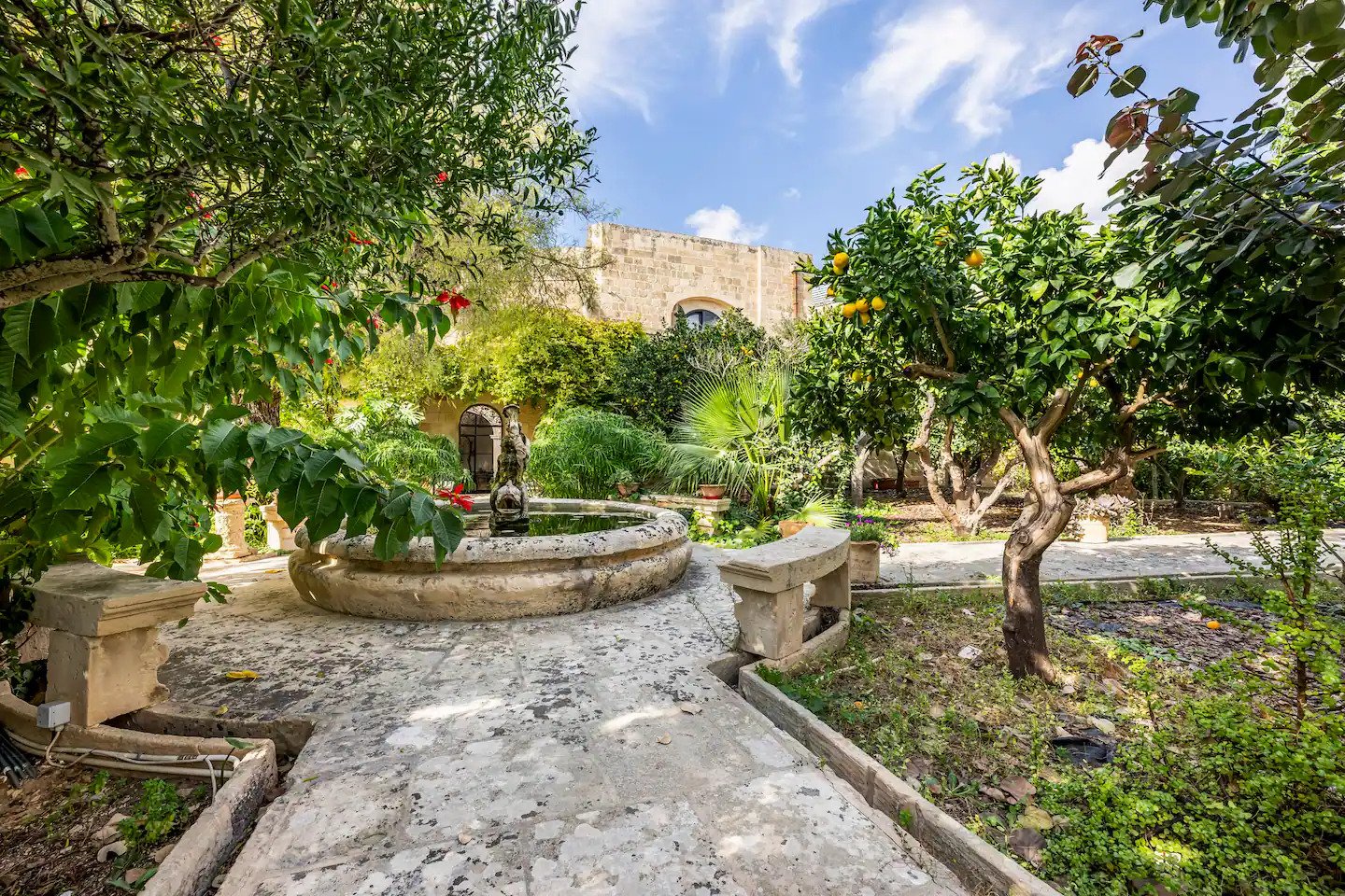 A stone fountain surrounded by greenery in the private garden